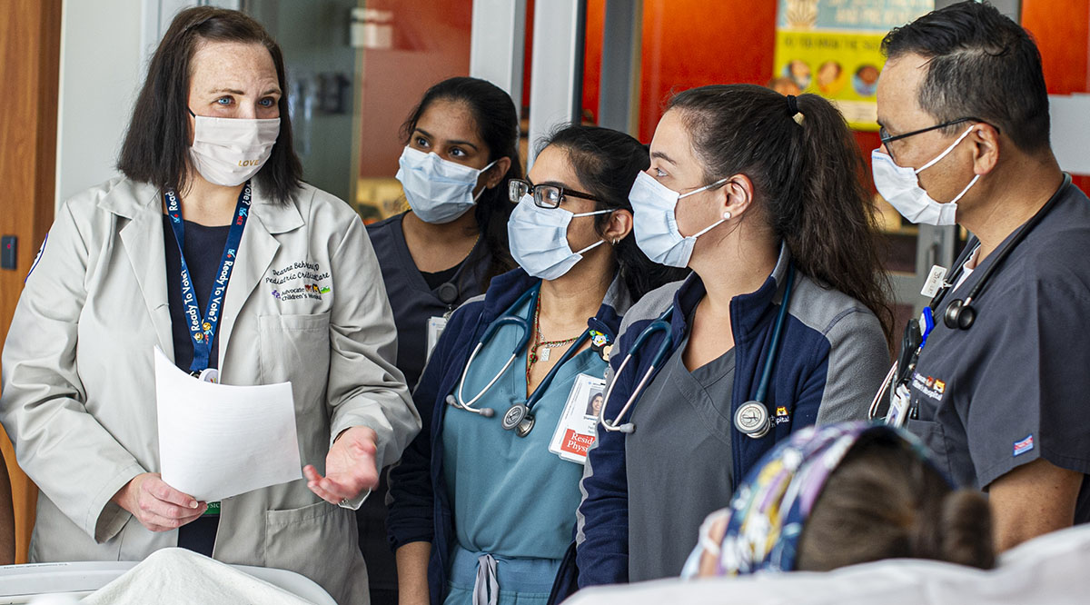 Deanna Behrens, MD, a pediatrician at Advocate Children’s Hospital in Park Ridge, Illinois, discusses a COVID-19 patient with staff in the pediatric intensive care unit.