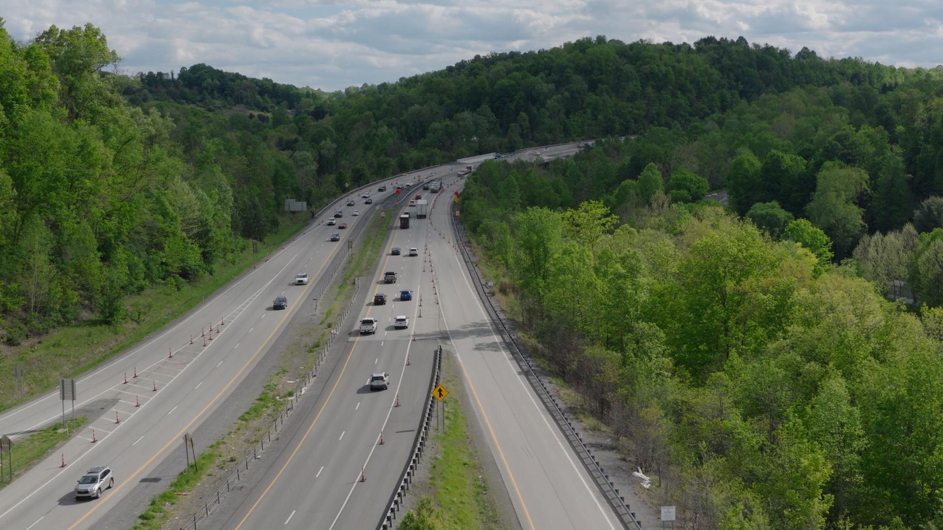 an aerial view of a highway weaving through rolling green hills