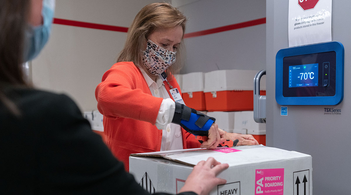 Lynn Combs, medication procurement coordinator at the University of Virginia Medical Center Pharmacy, unpacks the first shipment of COVID-19 vaccines for storage in a freezer set at minus 70 degrees Celsius.