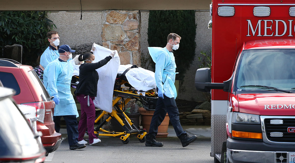 Health care workers transport a patient into an ambulance