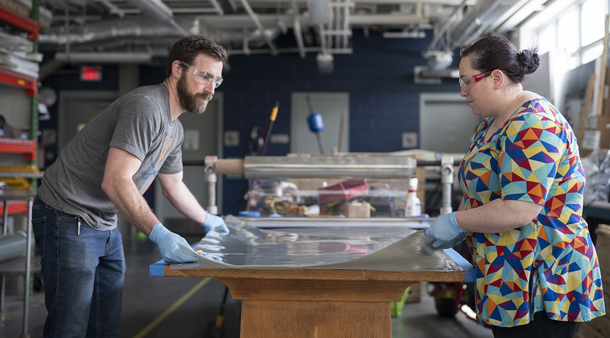 Engineering_UVA_Masks Trevor Kemp, assistant manager of the University of Virginia School of Architecture’s FabLab, and Melissa Goldman, manager of the FabLab, prepare plastic film to be cut for face shields