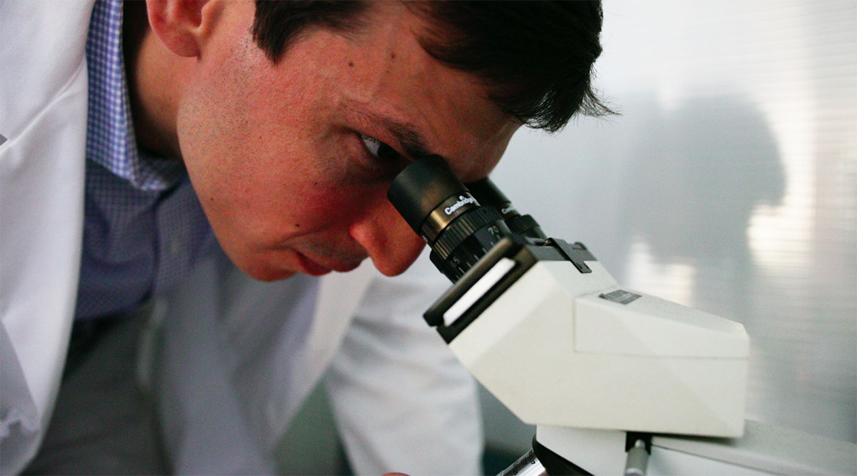 DavidFajgenbaum_AtMicroscope In 2014, David Fajgenbaum, MD, MBA, MSc, uncovered a potential treatment for his own deadly disease. Now he's on a mission to find one for COVID-19.