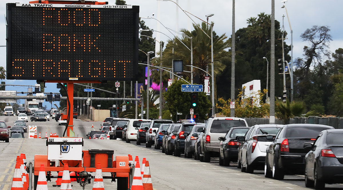 Cars line up at a free groceries distribution site for those impacted by the COVID-19 pandemic on April 10, 2020 in Inglewood, California.