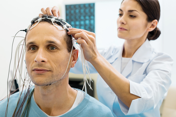 A female doctor putting electrodes on the head of her patient.