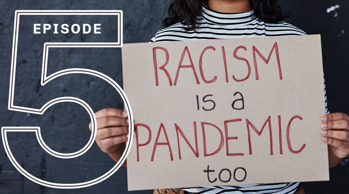A person holding a "Racism is a Pandemic too" sign