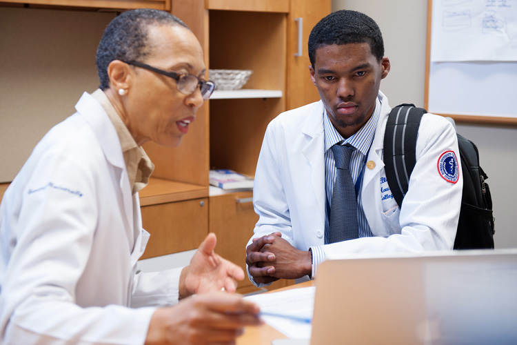 A male medical student and professor looking at the laptop.