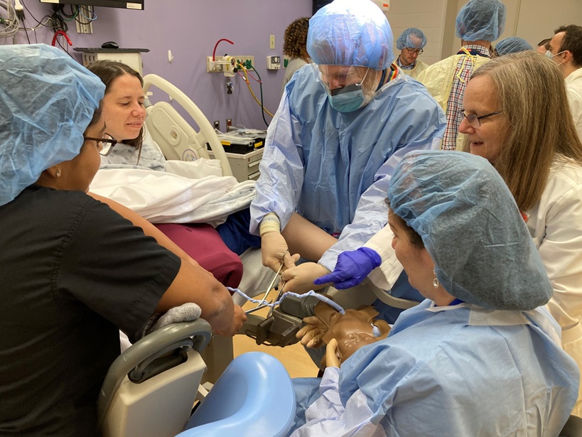 Medical students practice delivering a baby