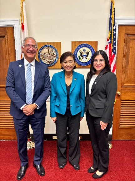  John Dalrymple, Judy Chu, and Bianka Aguirre standing in front of United States seal and flag.