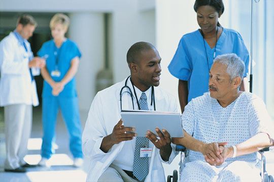 WH-Medicaid-0605 A doctor explains paperwork to a patient in a wheelchair while a nurse pushes him.
