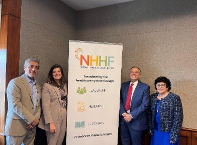Briefing participants stand next to a NHHF sign