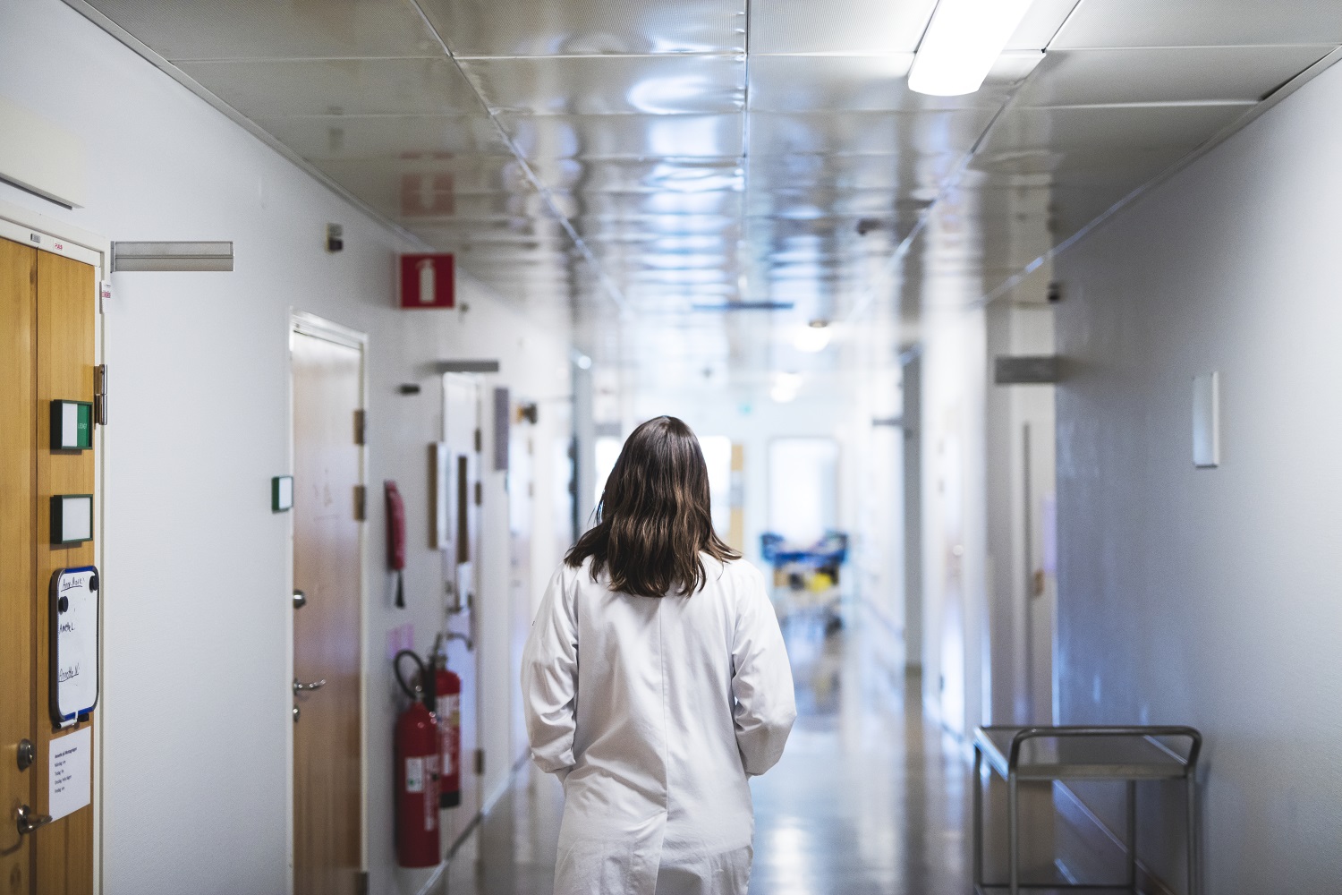 Why women leave medicine Female doctor walks down a hospital hallway.