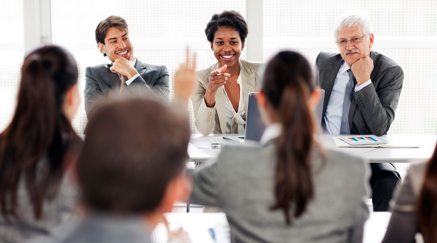 Achieving Gender Equity Is Our Responsibility: Leadership Matters A woman takes questions at a meeting while two male colleagues look on supportively.