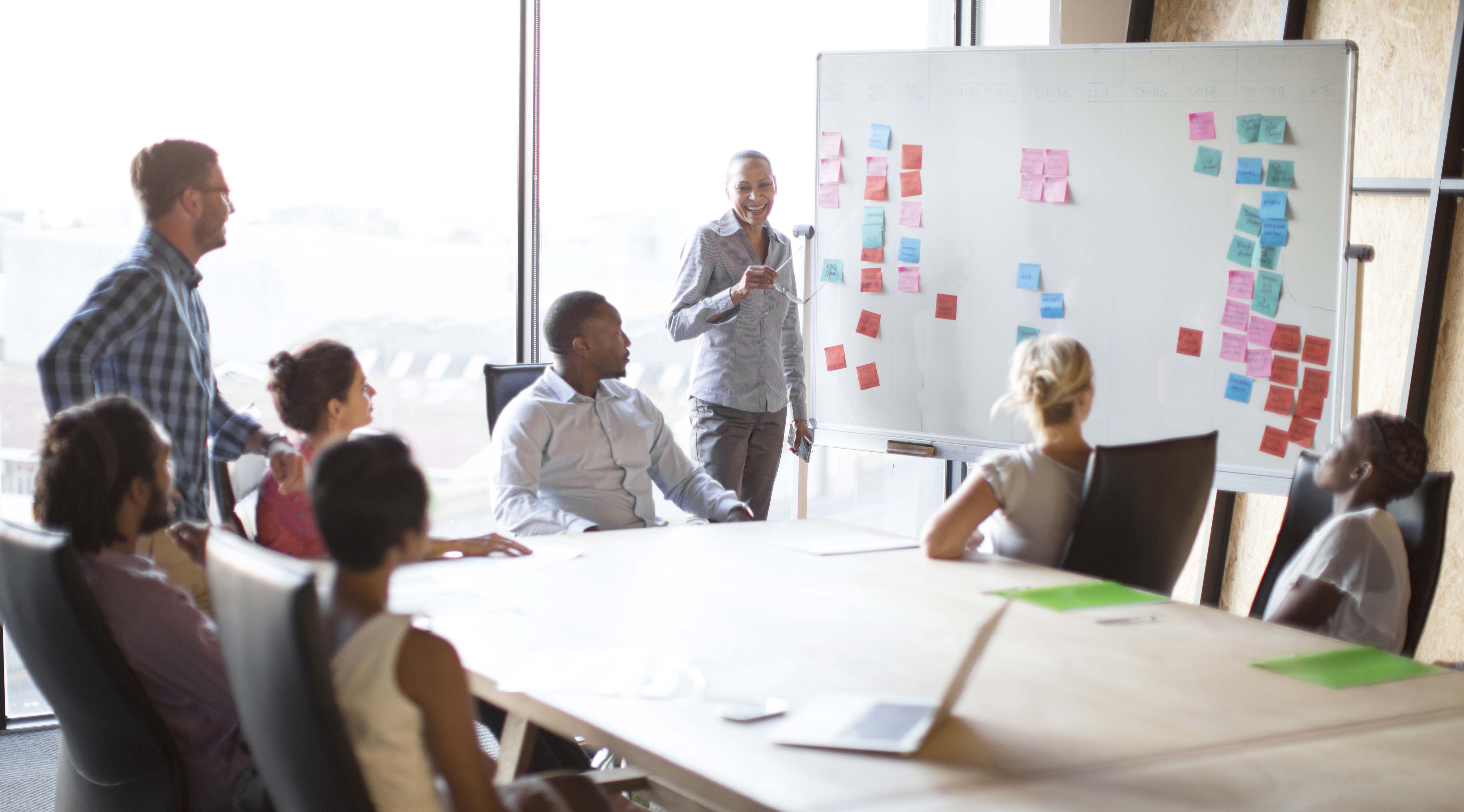 A woman leads a meeting of her colleagues to discuss goals.