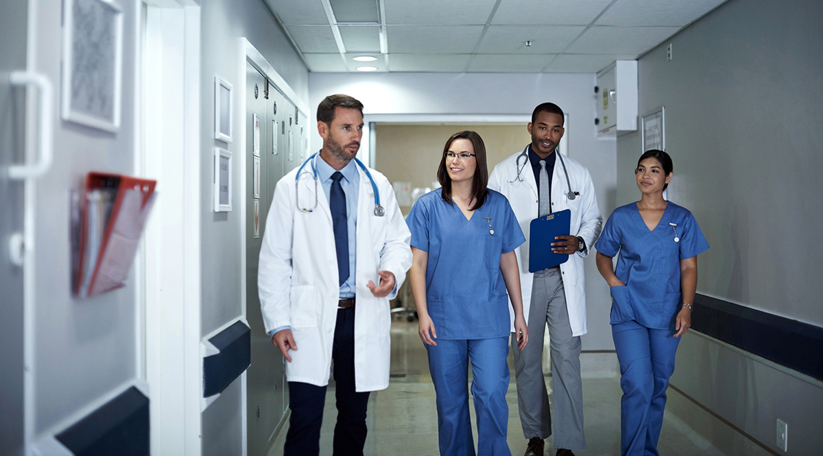 StandPoint Surveys Health Professionals A group of male and female colleagues walk down a hospital hallway.