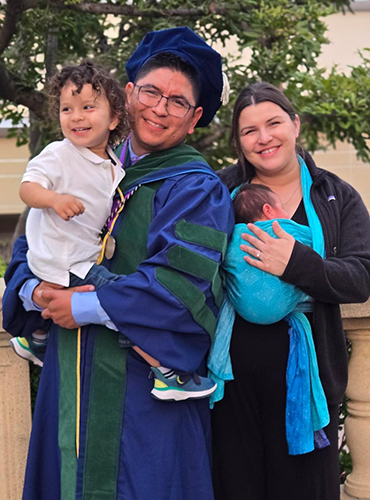 Jesus Eduardo Fuentes, MD, poses with his partner, Tabitha Kirkendall, and their two sons at his medical school graduation.