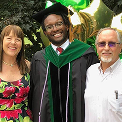 Christopher Veal, MD, at his 2021 medical school graduation with his godparents, who helped him through his darkest time.