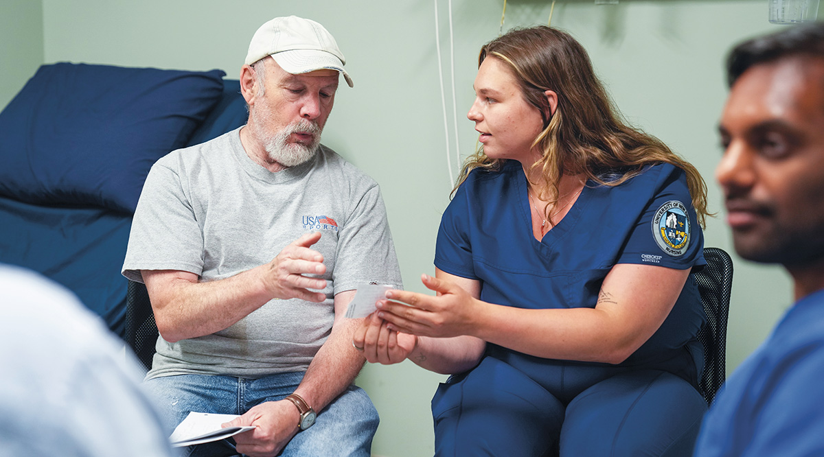 “Michael,” a standardized patient, chats with third-year nursing student Alexa Lanteri and first-year medical student Varun Kota, at the University of New England.