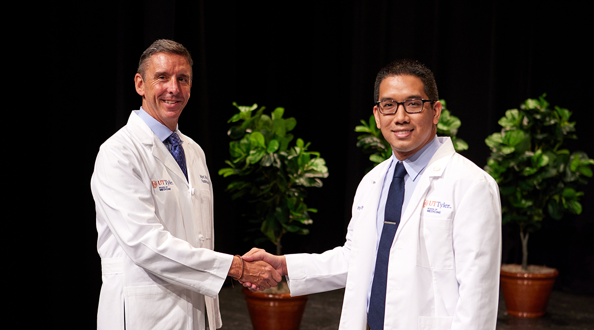 Tony Phan, right, shakes hands with Brigham C. Willis, MD, founding dean of the University of Texas at Tyler School of Medicine, at Phan’s White Coat Ceremony in July 2023.
