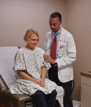 A medical student performing a physical exam on a simulated patient.