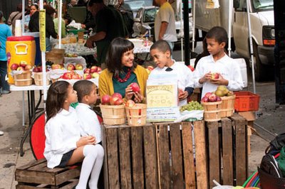a woman talking to children at a farmers' market
