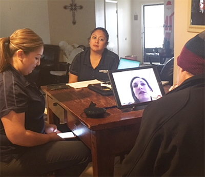 Home visit with 2 nurses and patient looking at computer on table