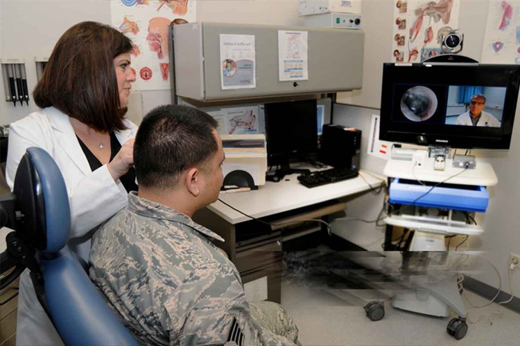 Erica Taylor demonstrates using the Telehealth cart otoscope to conduct a real-time exam to Physician Assistant Steven Cain.