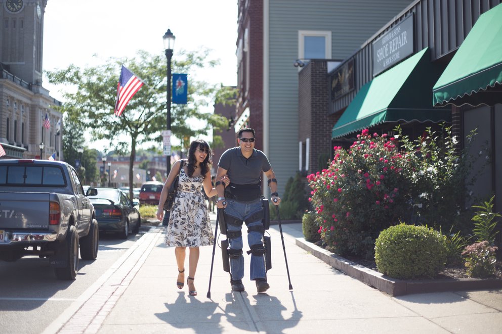 Man with exoskeleton walking with woman