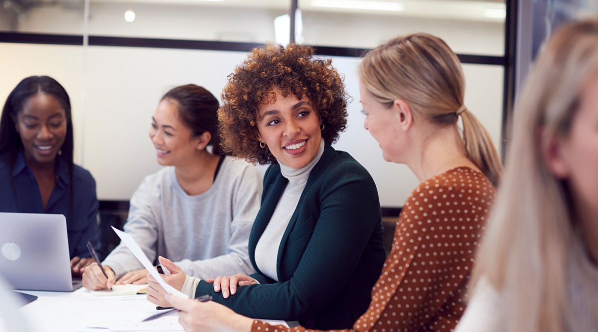 Group of businesswomen collaborating in creative meeting around table in modern office