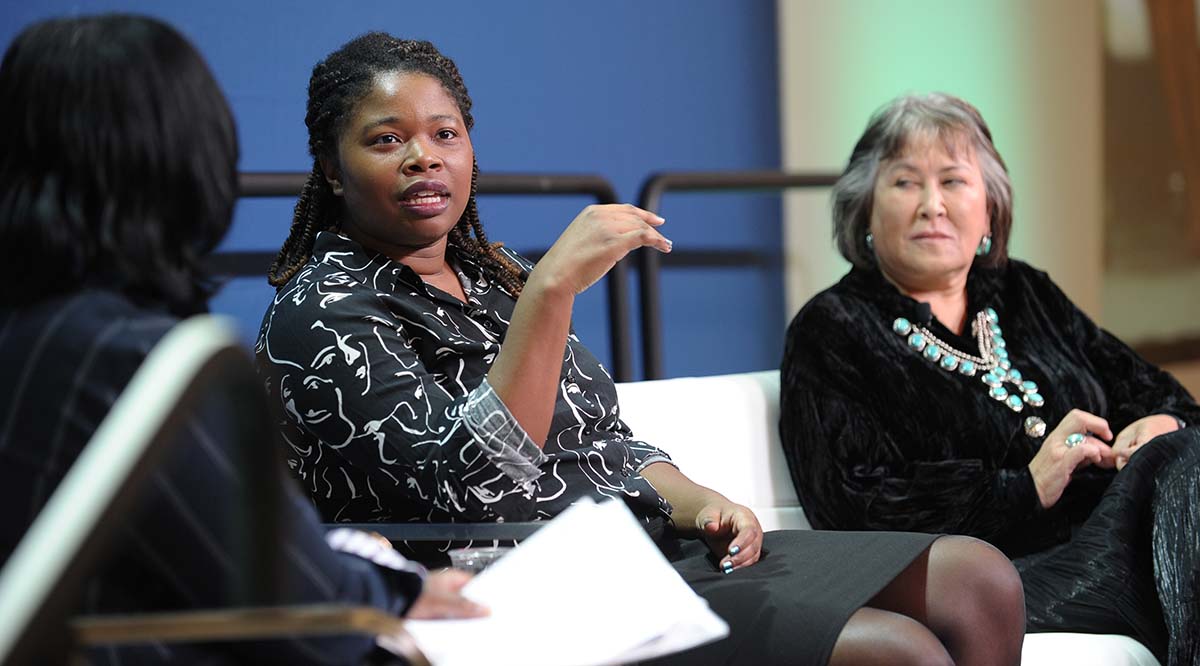 Jasmine Brown, M Phil, speaks on stage while sitting alongside Lori Alvord, MD, during Learn Serve Lead 2023.