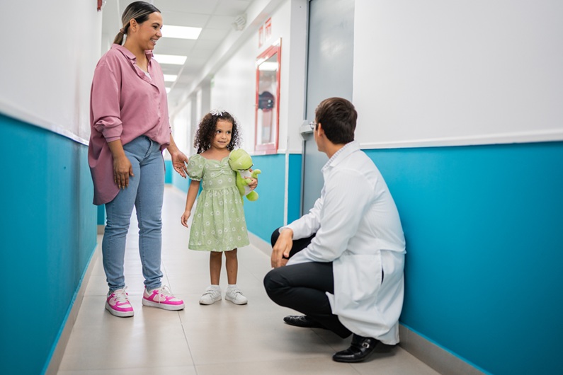 Mother and daughter talking to doctor on corridor at hospital