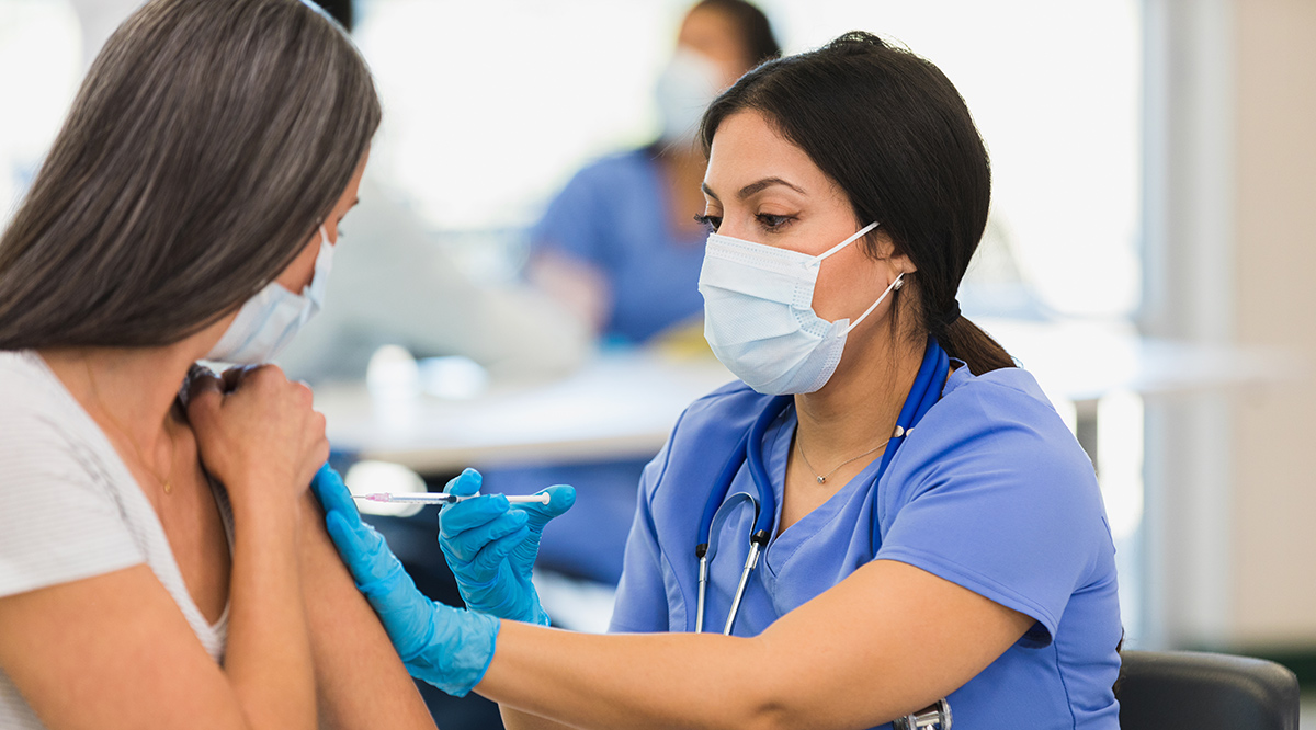 A female nurse giving a vaccine to a woman at a vaccination center