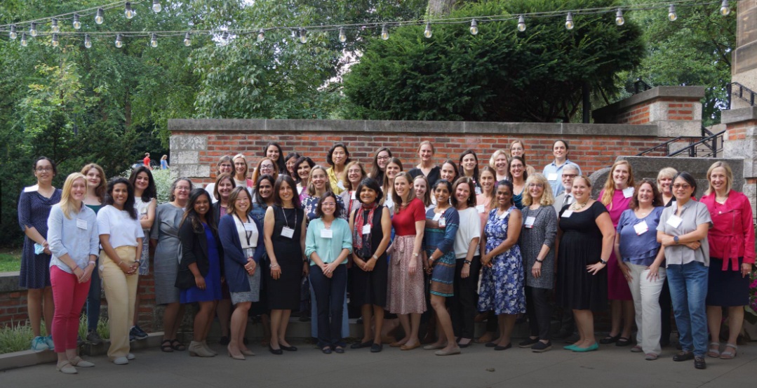 Members of the OSU WIMS program gather for a group photo in front of a brick wall