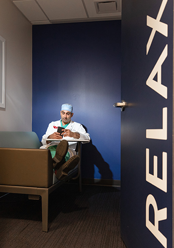 A man in scrubs sits at the wellness lounge of UNMC.
