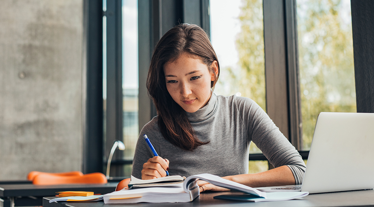 Young female student in library in front of a computer