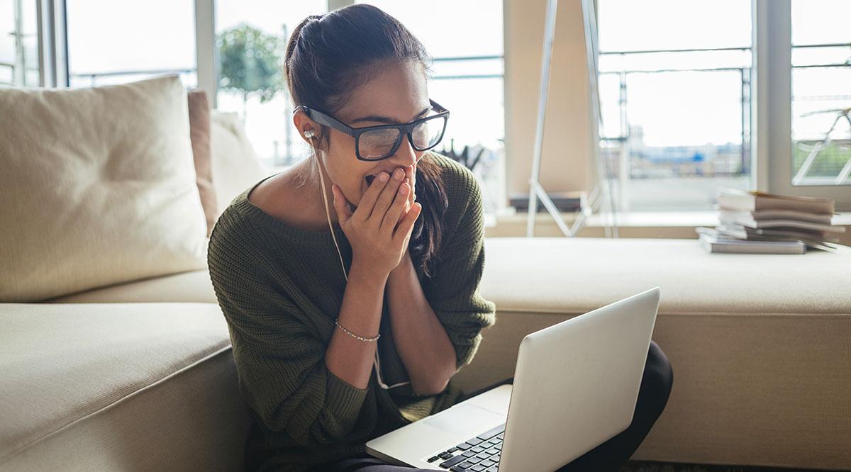 A woman looks excited as she stares at her laptop