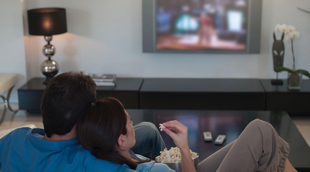A couple watches a movie on a TV screen