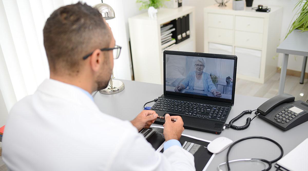 A male doctor consults with an elderly female patient through the computer.