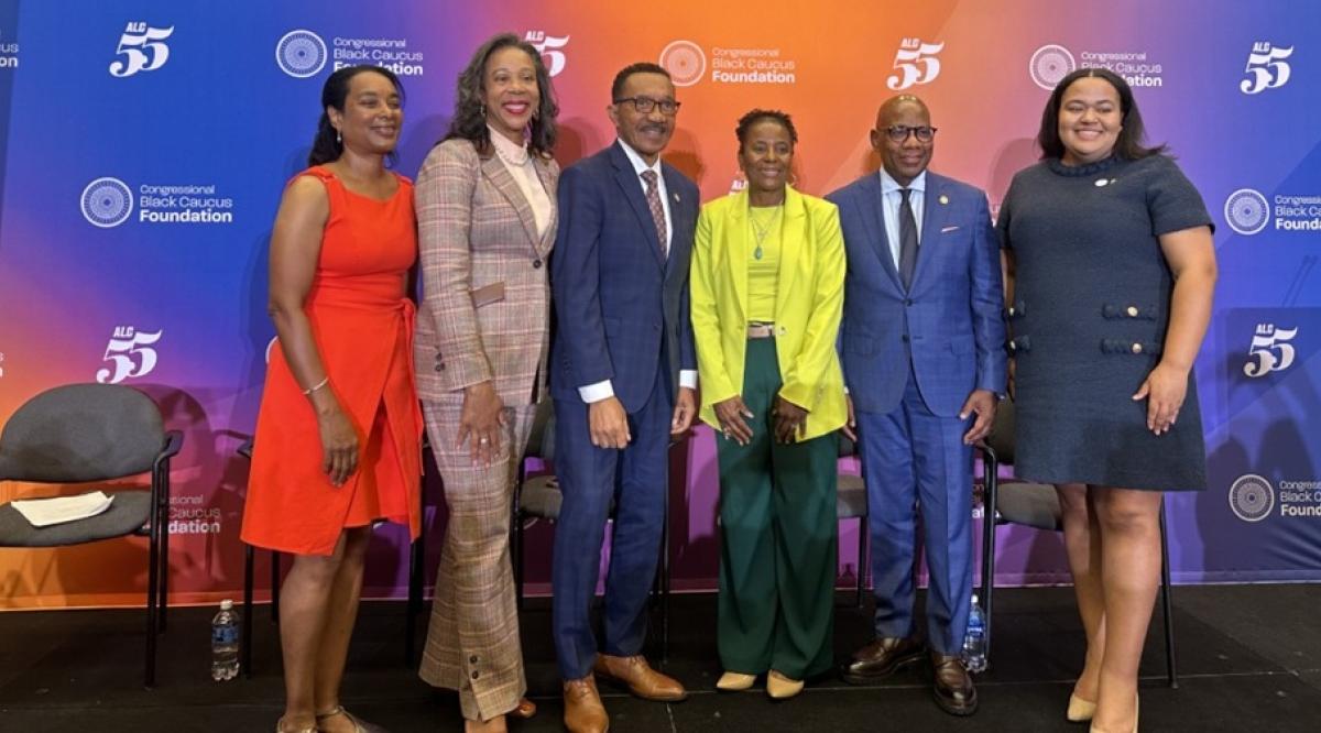 Panel members pose in front of a colorful conference backdrop