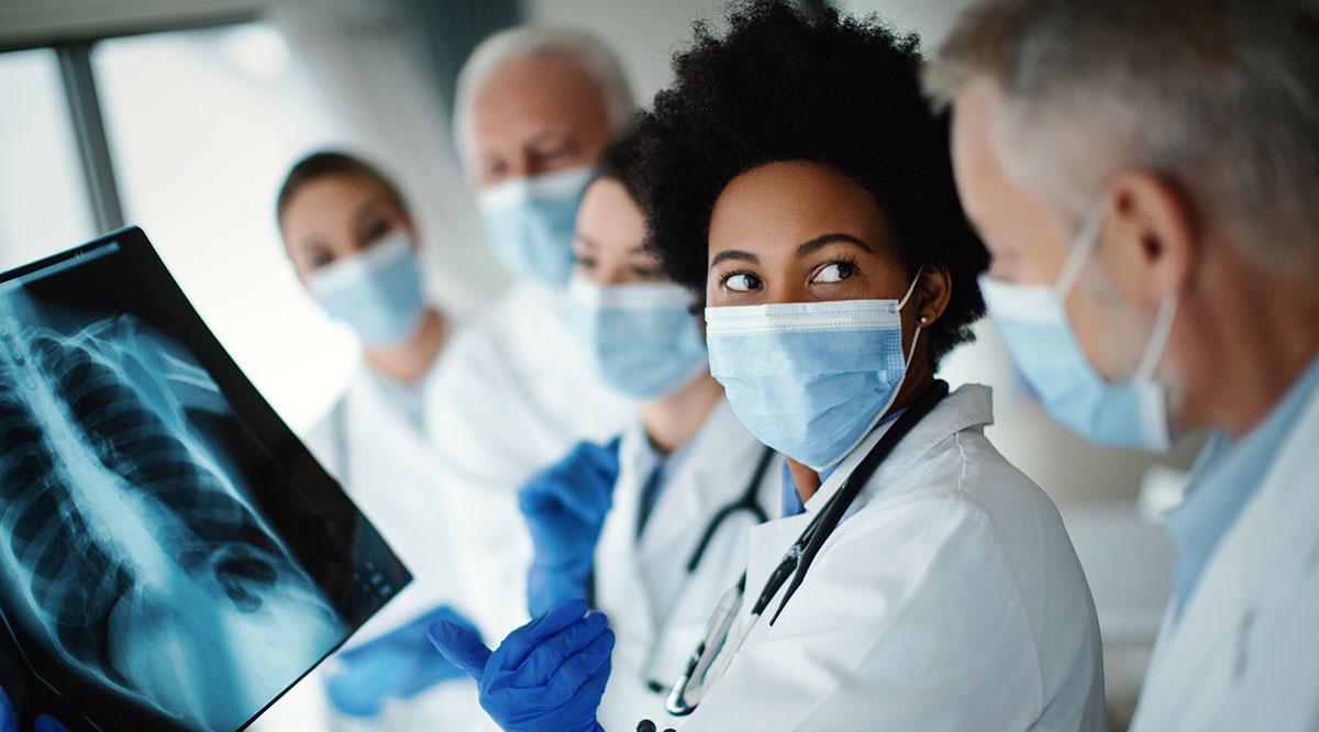 A group of masked doctors look at an x-ray