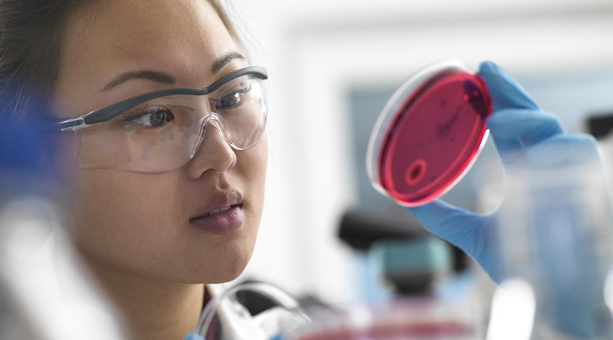 a woman holding up a petri dish