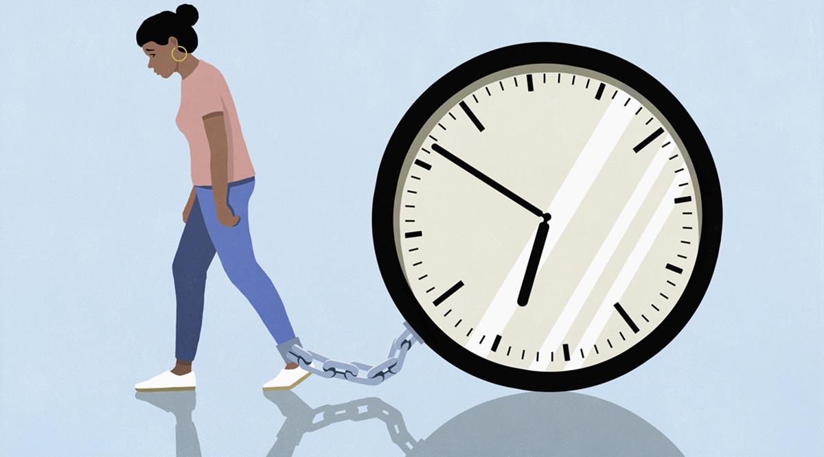 Woman dragging large clock chained to her ankle against blue