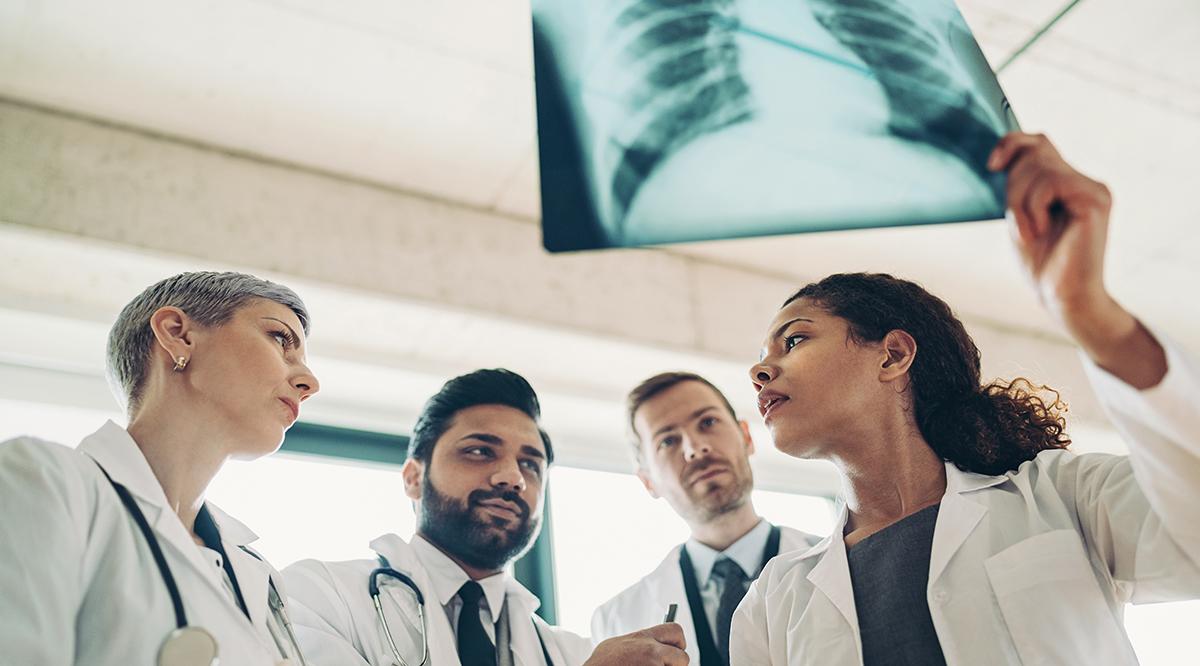 Female doctor showing an x-ray image of man's lungs to her colleagues