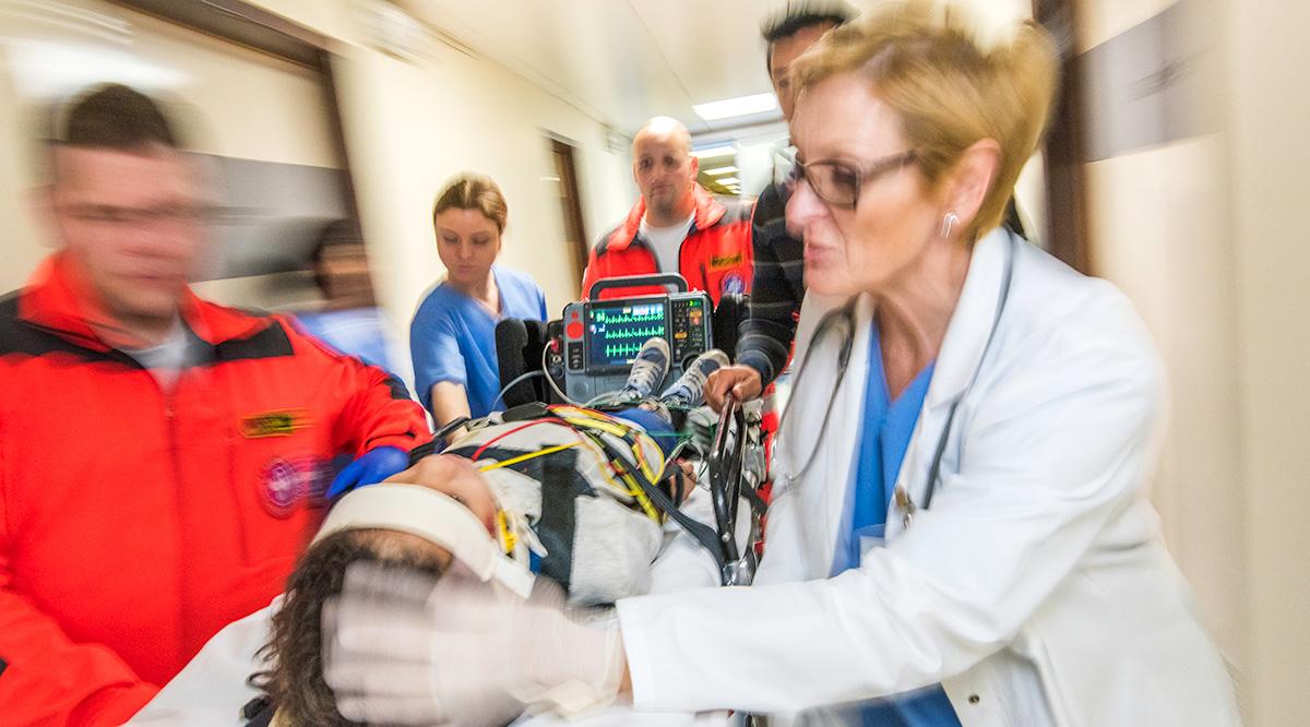 Paramedics and female doctor pulling hospital trolley