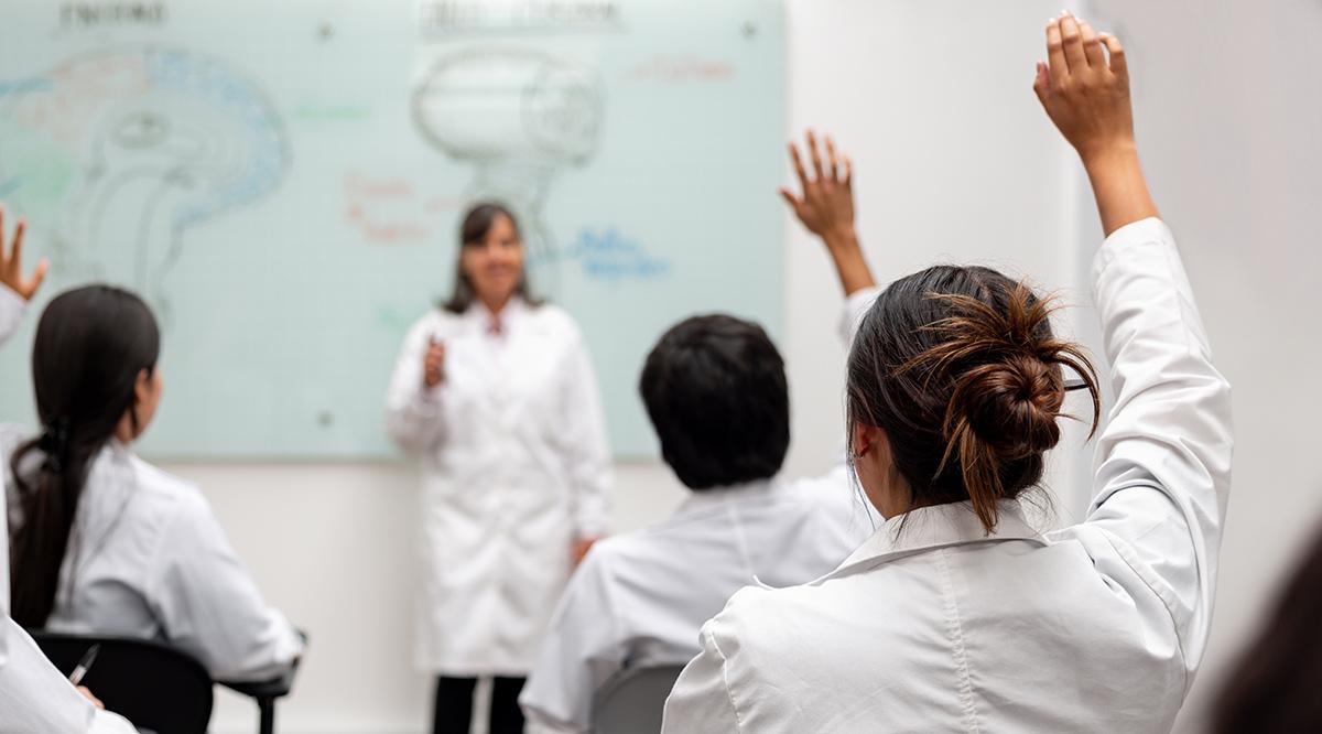 Medical students raising their hand to ask questions in class