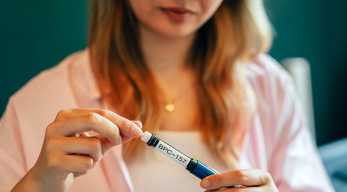 Woman holding BPC-157 peptide injection pen at home