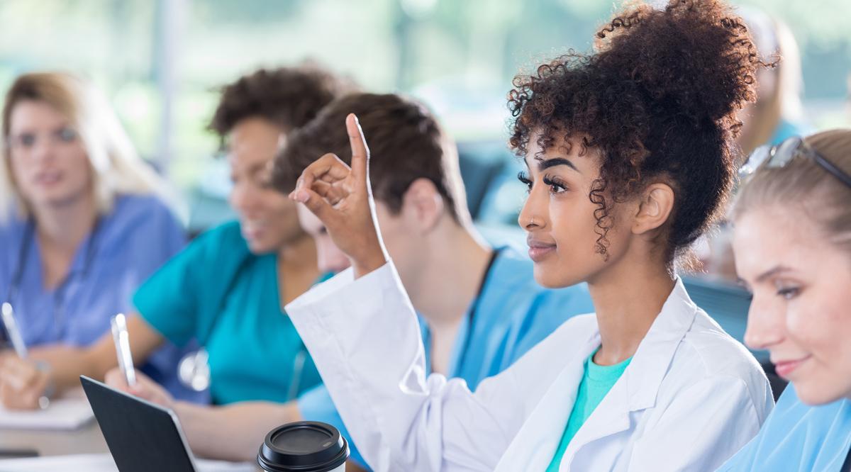 A female resident raises her hand to ask a question in class.