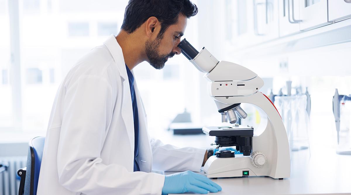 Scientist in laboratory looking into microscope
