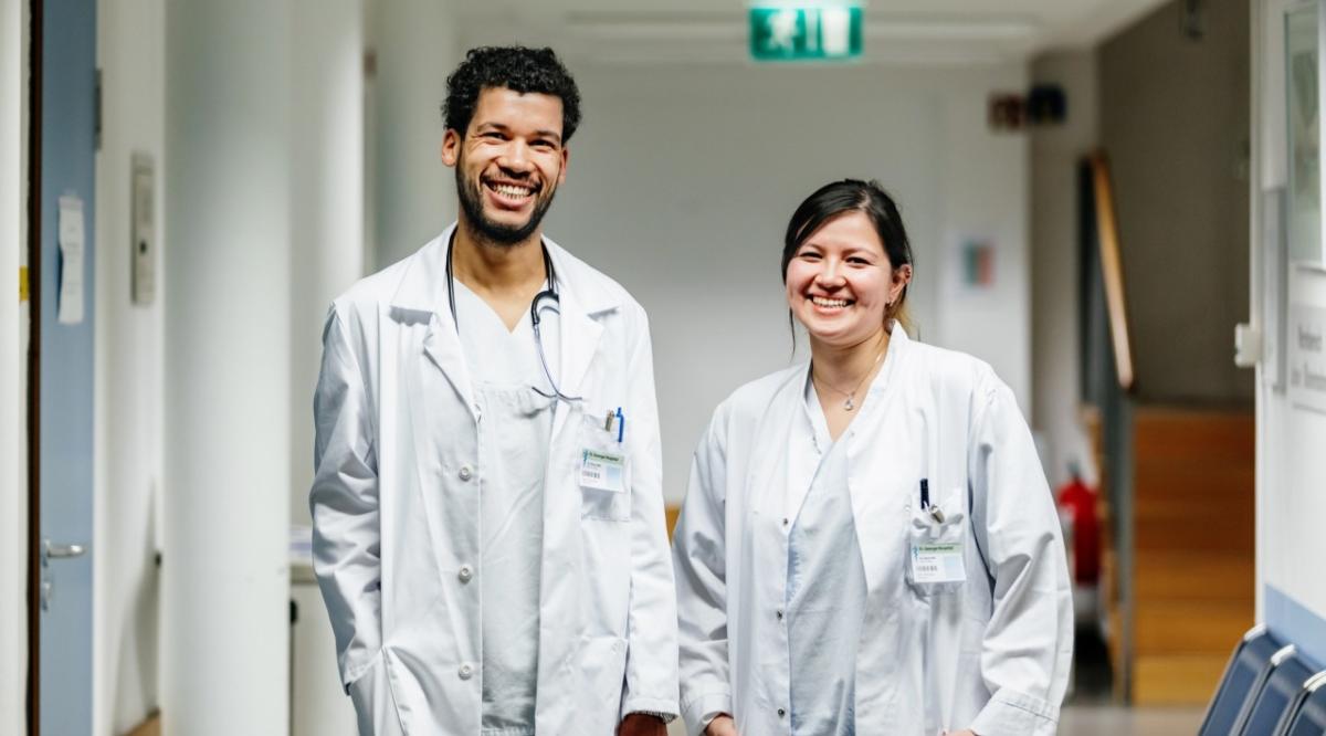 two doctors smile in white coats
