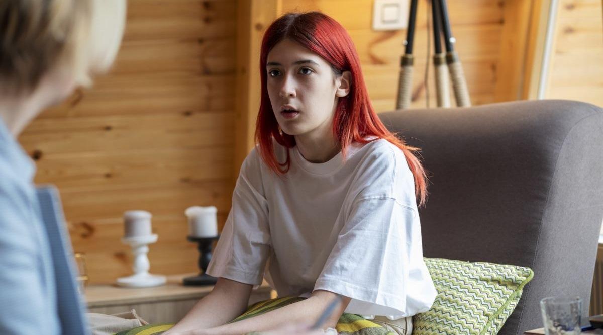 A young woman siting on a psychiatrist's couch in the consulting room and talking to her therapeutic practitioner.