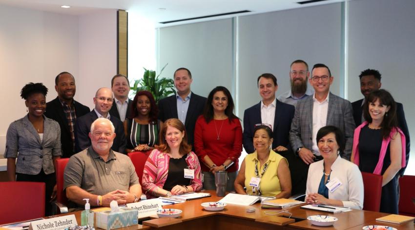 Members of the AMCAS Advisory Committee and AMCAS team sitting around a conference table and posing for a picture.
